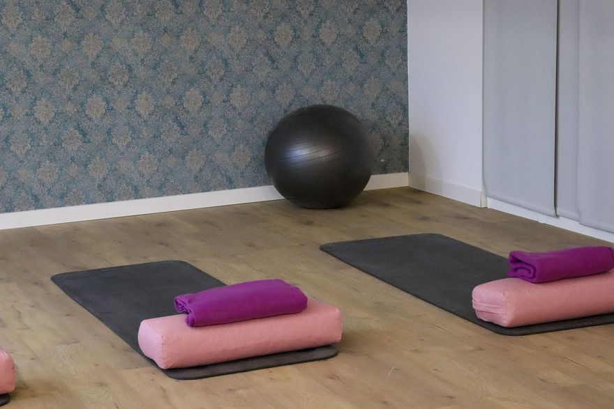 Ausgelegte Gymnastikmatten mit Nackenrollen und Handtüchern im Kursraum